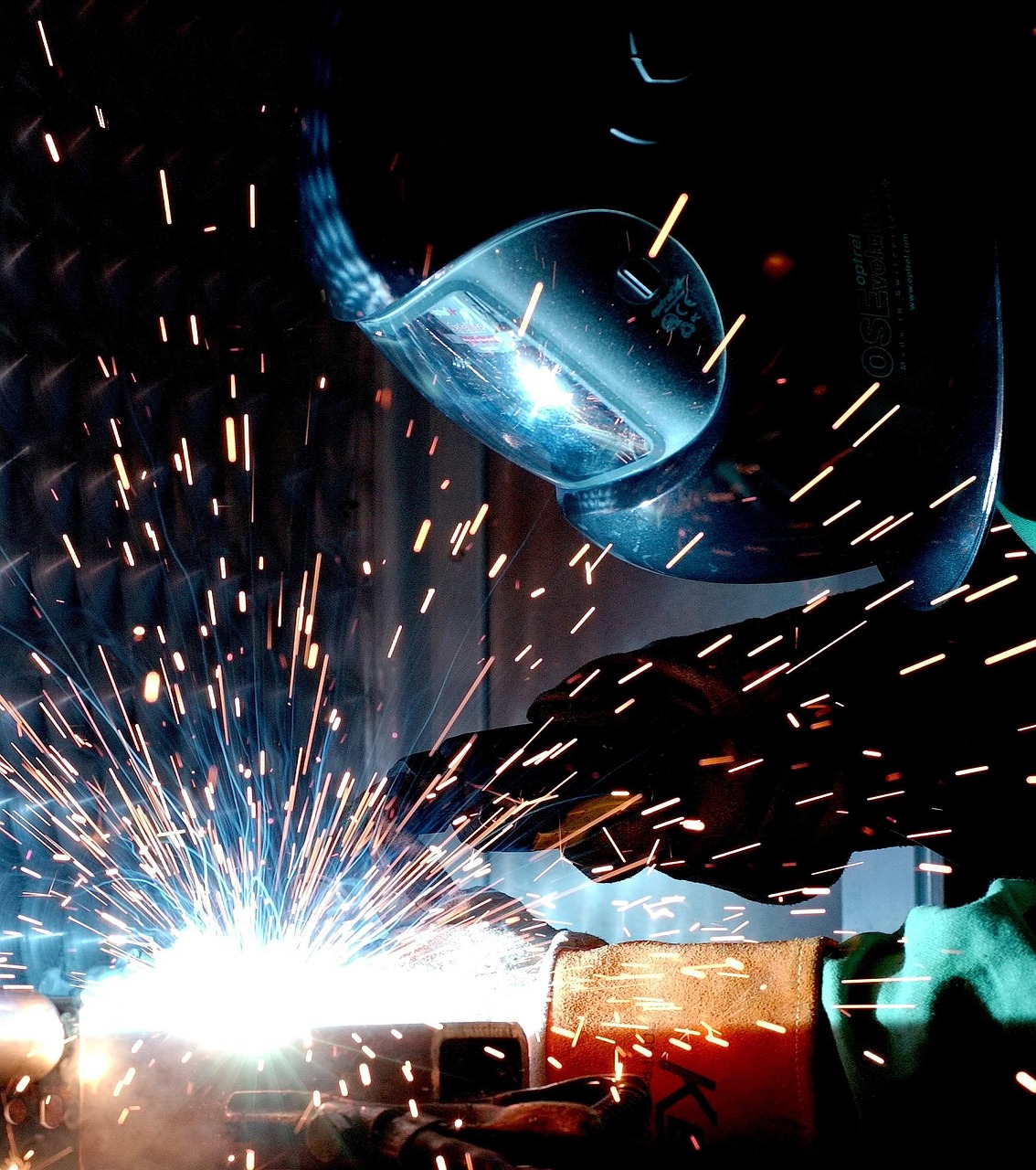 Trabajador industrial con guantes de protección realizando un proceso de soldadura